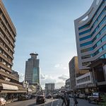 Harare, Zimbabwe - March 15, 2016: A modern office block rises above the horizon in Harare, capital of Zimbabwe, at business closing time. The city is alive with commuters, mostly government officials working in the capital, on their way home. The country's economy is faltering, its government officials working in the city often not paid on time as Zimbabwe struggles to overcome economic sanctions brought about by the regime of the ageing President Robert Mugabe.